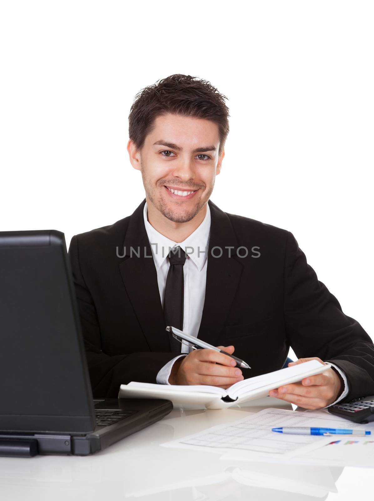 Handsome young businessman concentrating on making a note in his diary or scheduling an appointment or meeting