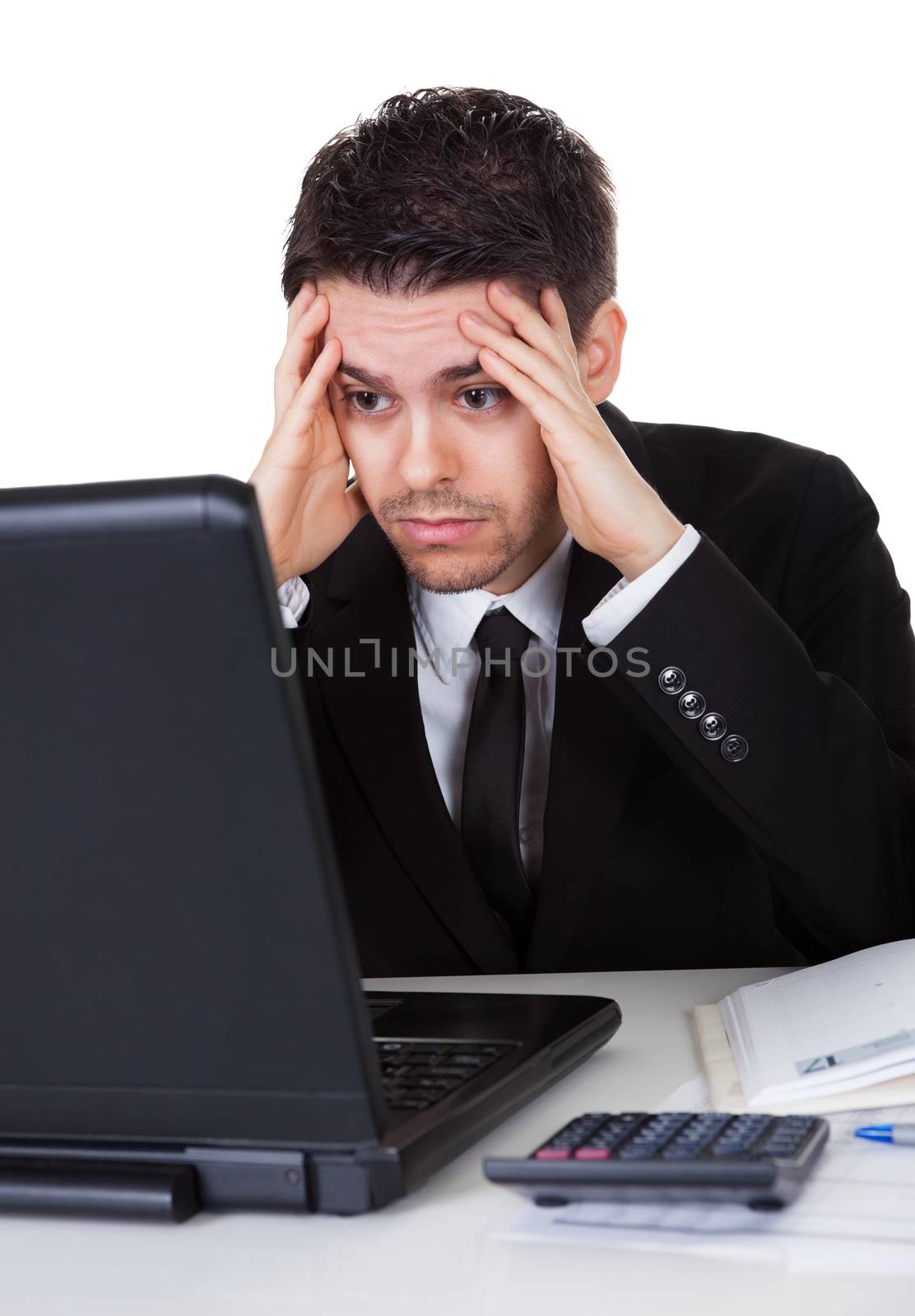 Businessman with a look of hopelessness staring at the screen of his laptop with his head resting in his hands