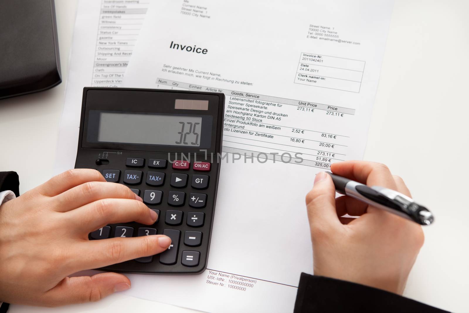 High angle cropped view of the hands of a male accountant doing calculations on a manual calculator while analyzing a report