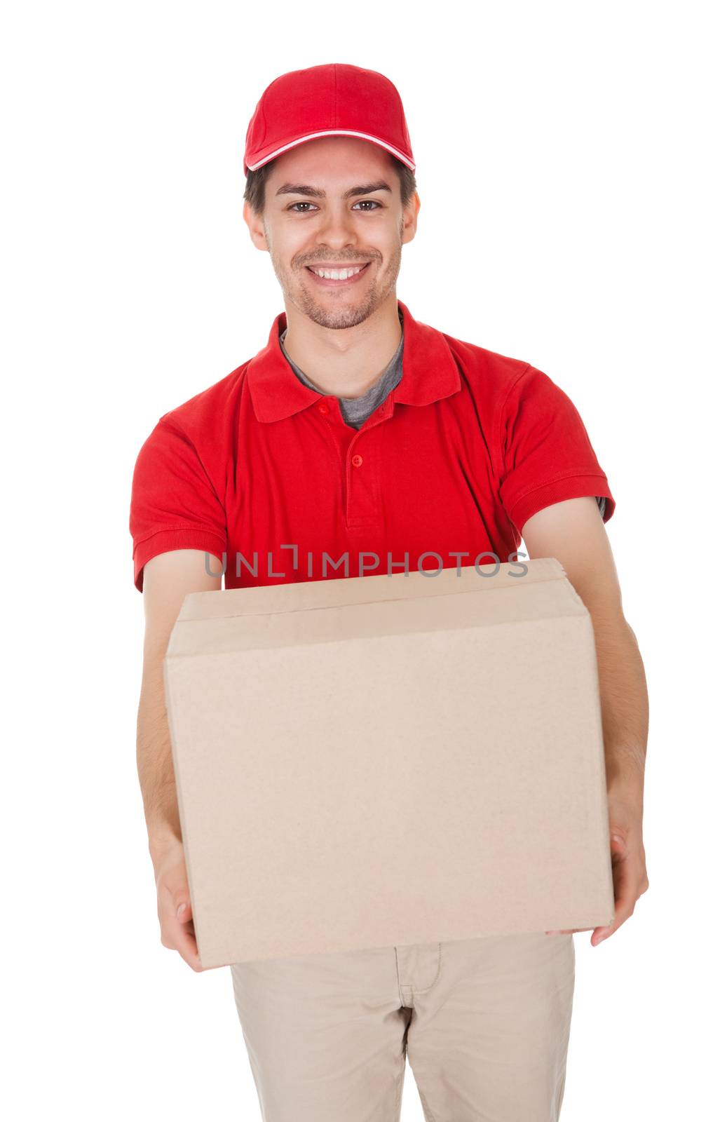 Smiling male courier in a red shirt and cap delivering a parcel in a brown cardboard box