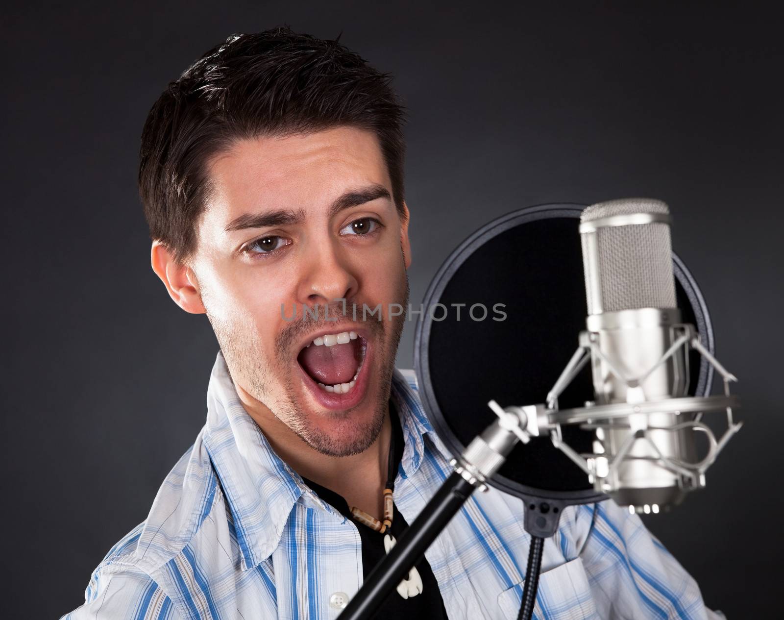 Portrait of young man singing into microphone