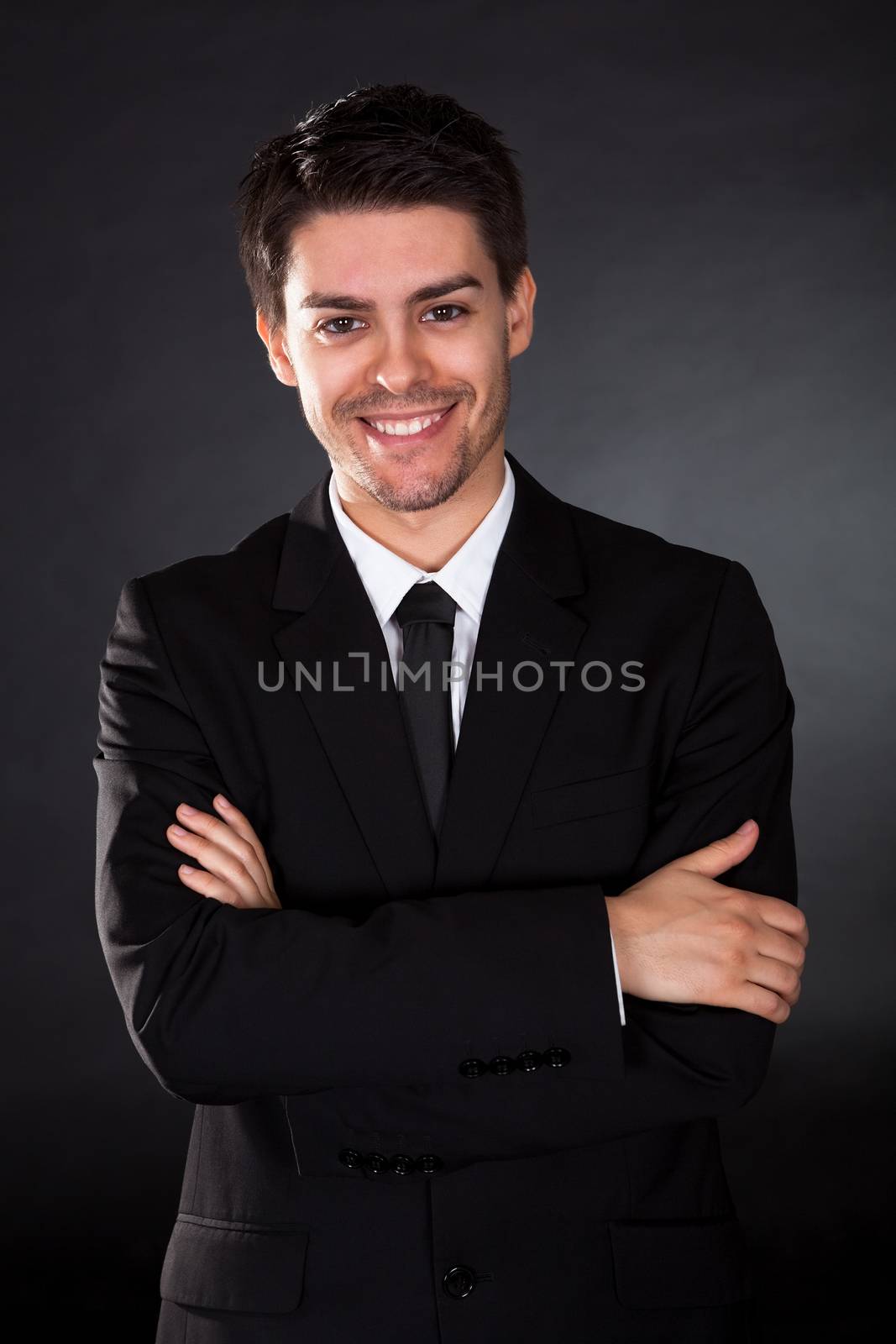 Portrait of smiling businessman over black background