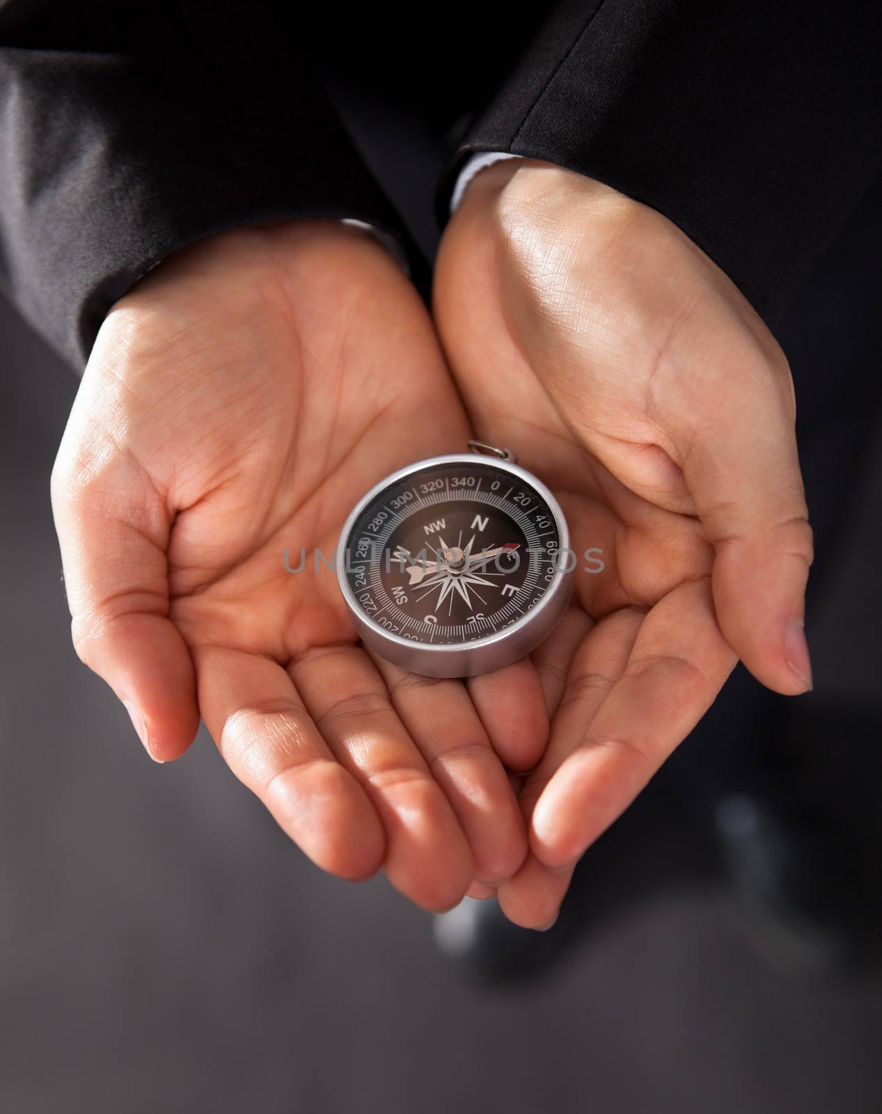 Businessman looking at a compass which he is holding in his hand with focus to the compass