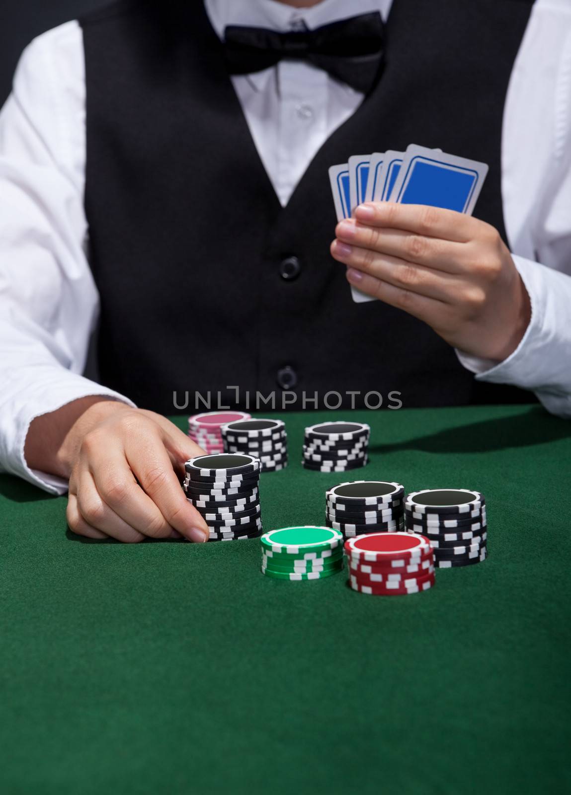 Male poker player about to place a bet moving a stack of tokens towards the centre of the gaming table with his free hand