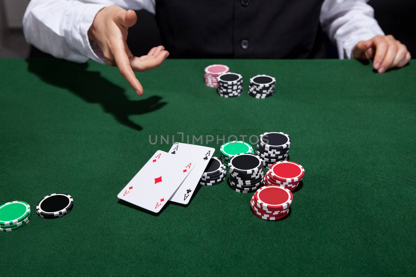 Poker player throwing down a pair of aces as he declares his hand and folds during a game of poker at a casino gaming table