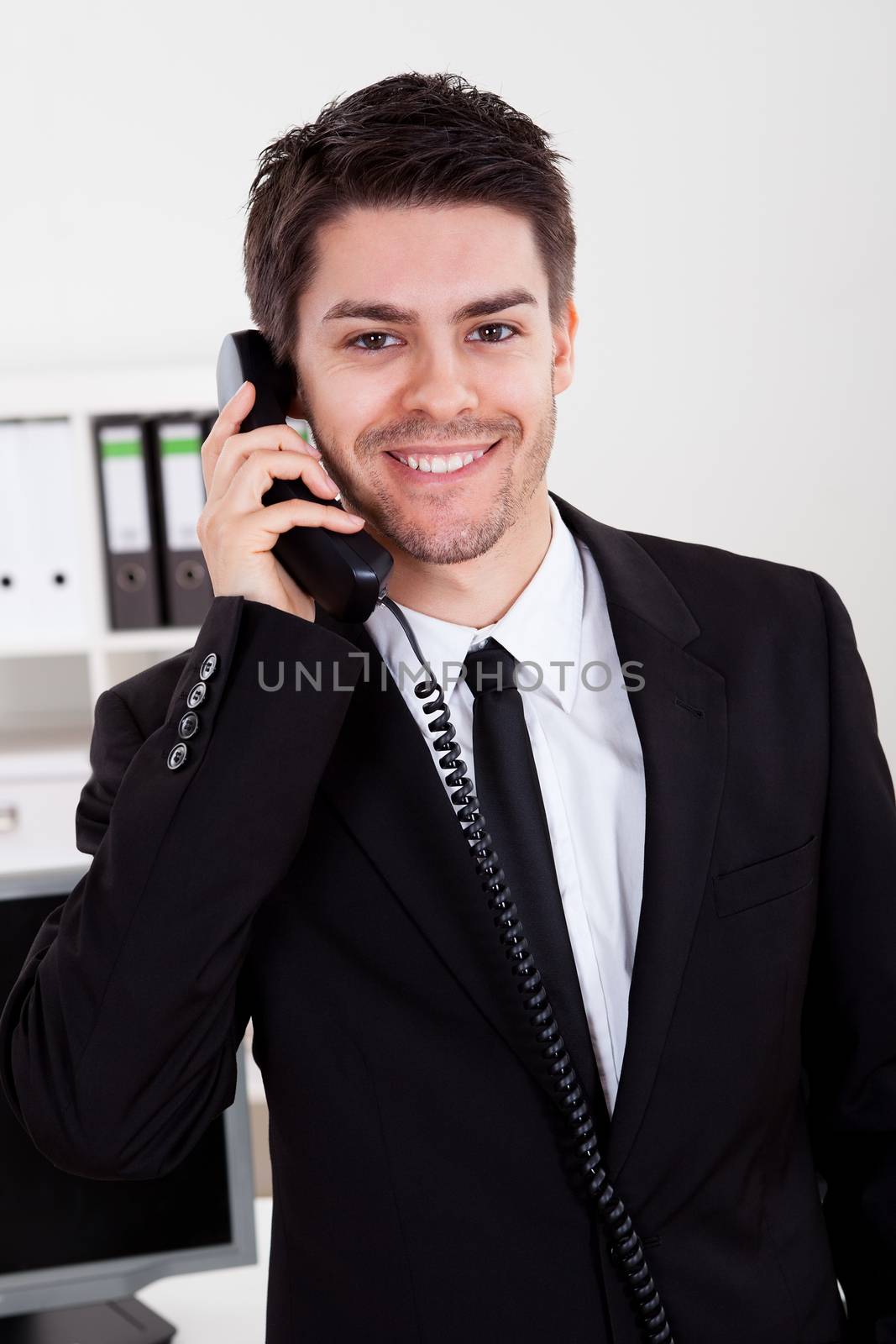 Enthusiastic young male stock broker in a bull market holding a telephone