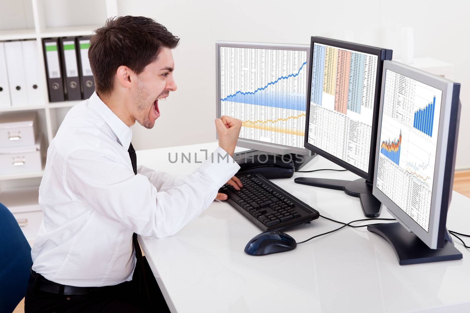 Over the shoulder view of the computer screens of a stock broker trading in a bull market showing ascending graphs