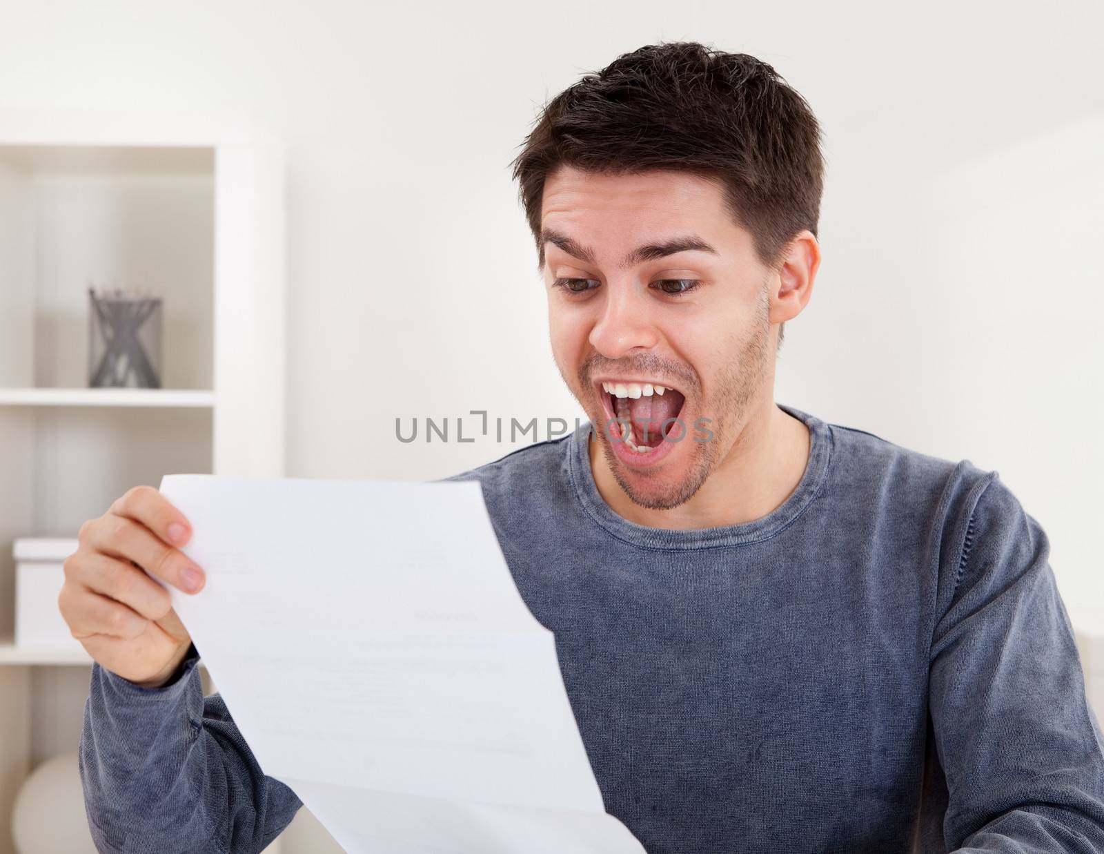 Exultant young man cheering at good news he has just received in a document that he is reading