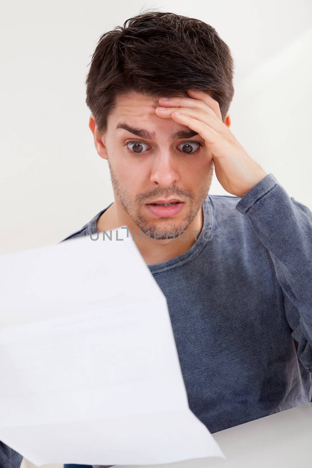 Horrified man reading a document by AndreyPopov