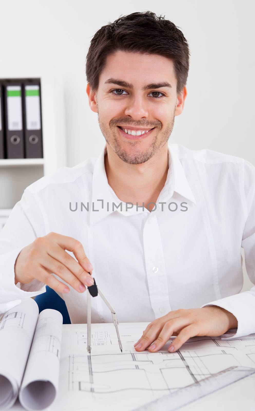 Closeup cropped image of a young male architect working on blueprints spread out on a table