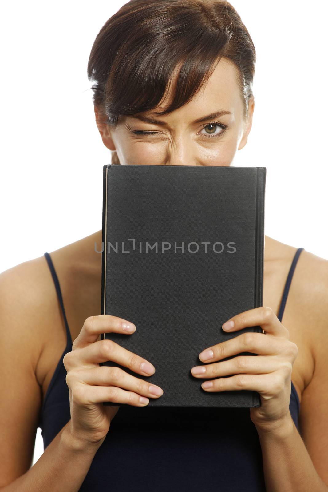 Young woman winking and holding a book in front of her.