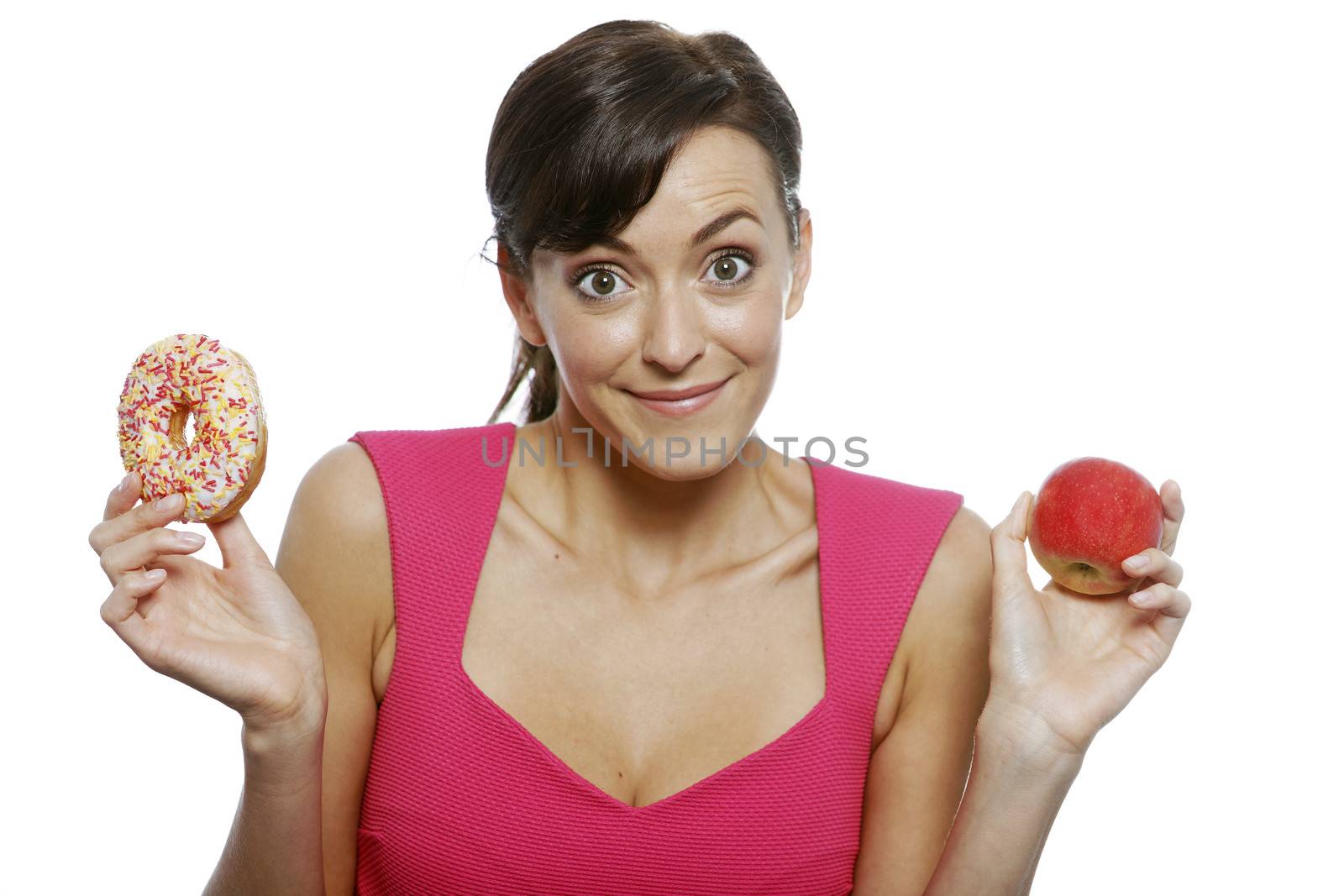 Young woman deciding between an apple or doughnut.