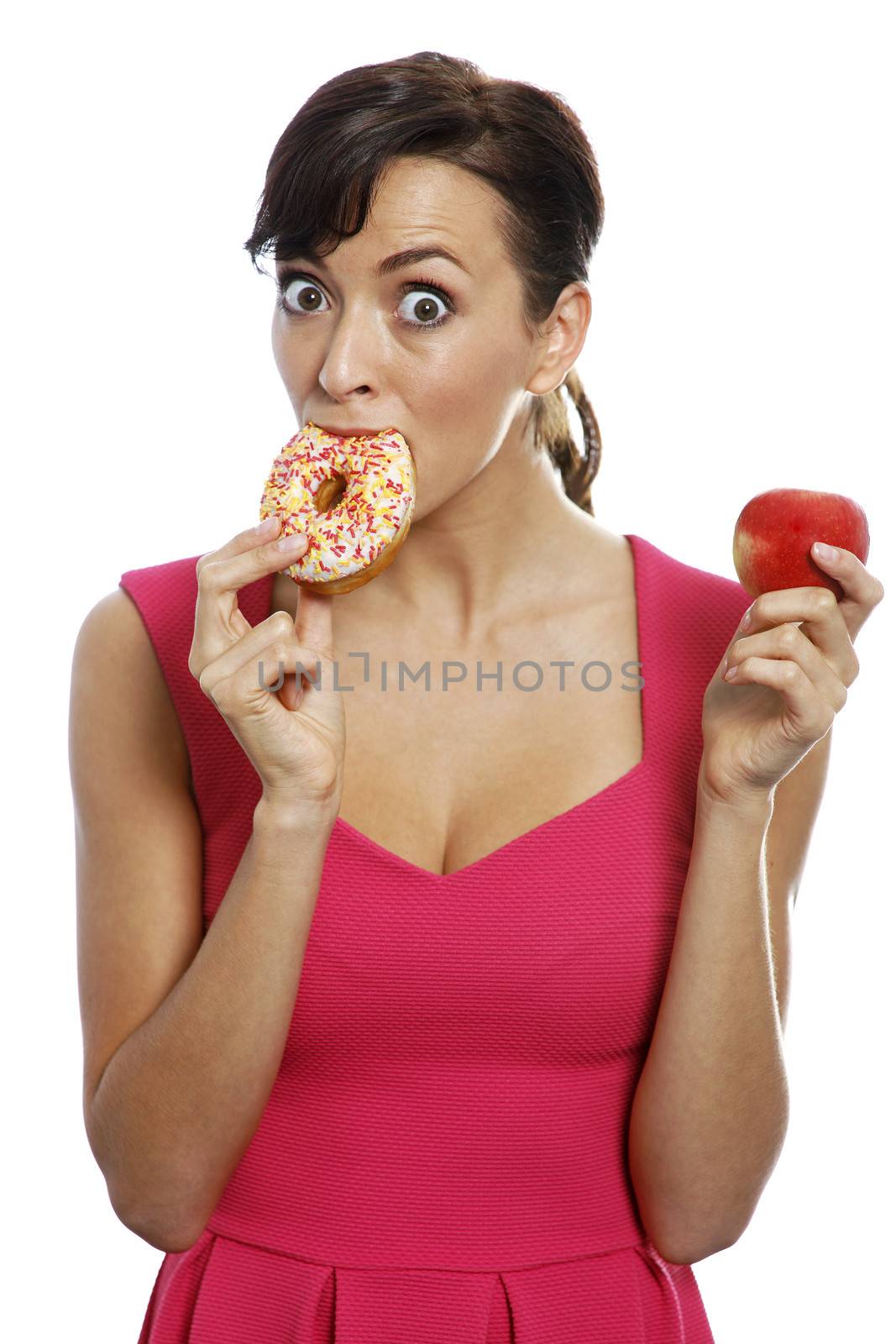 Young woman deciding between an apple or doughnut.