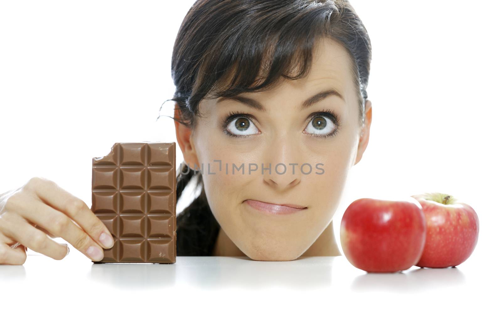 Young woman torn between a chocolate bar and fresh apple