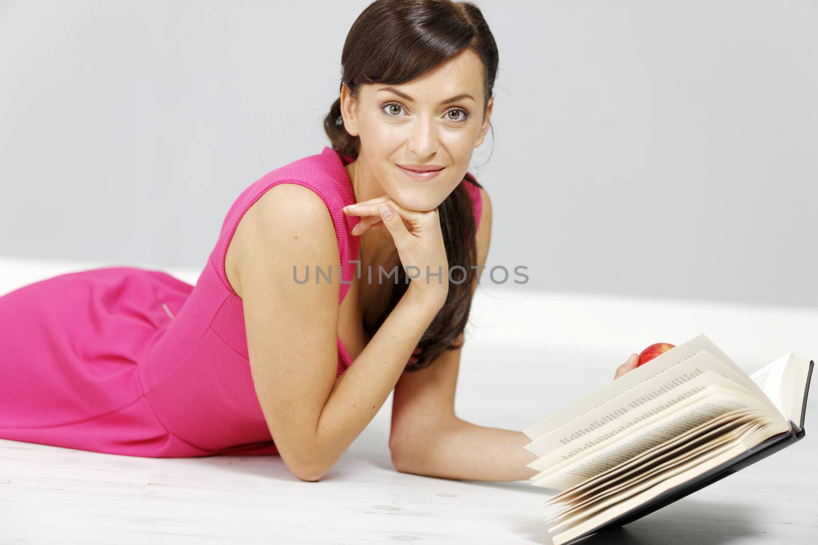 Young woman lying on the floor at home reading a book