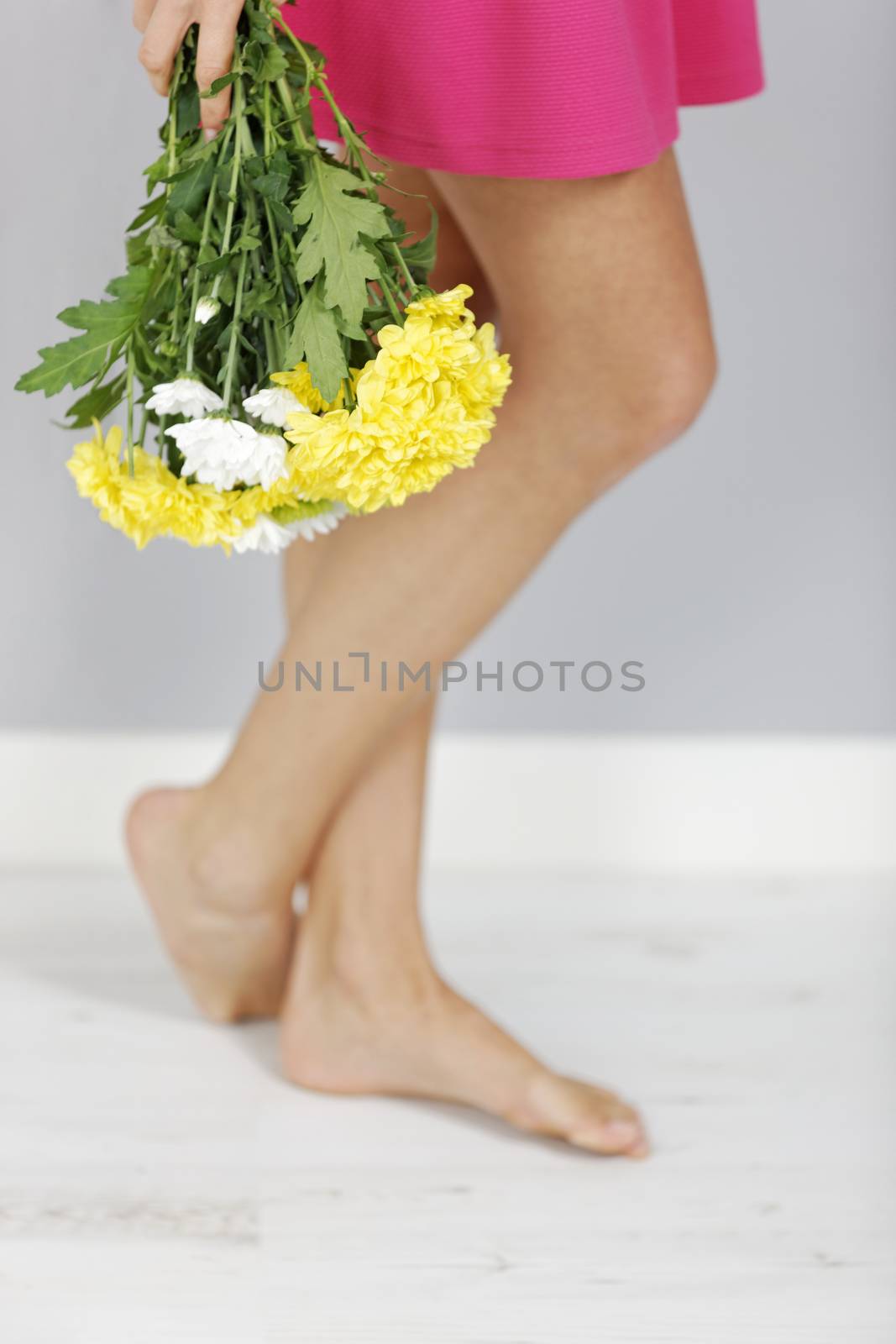 A fresh bouquet of flowers next to a woman's legs