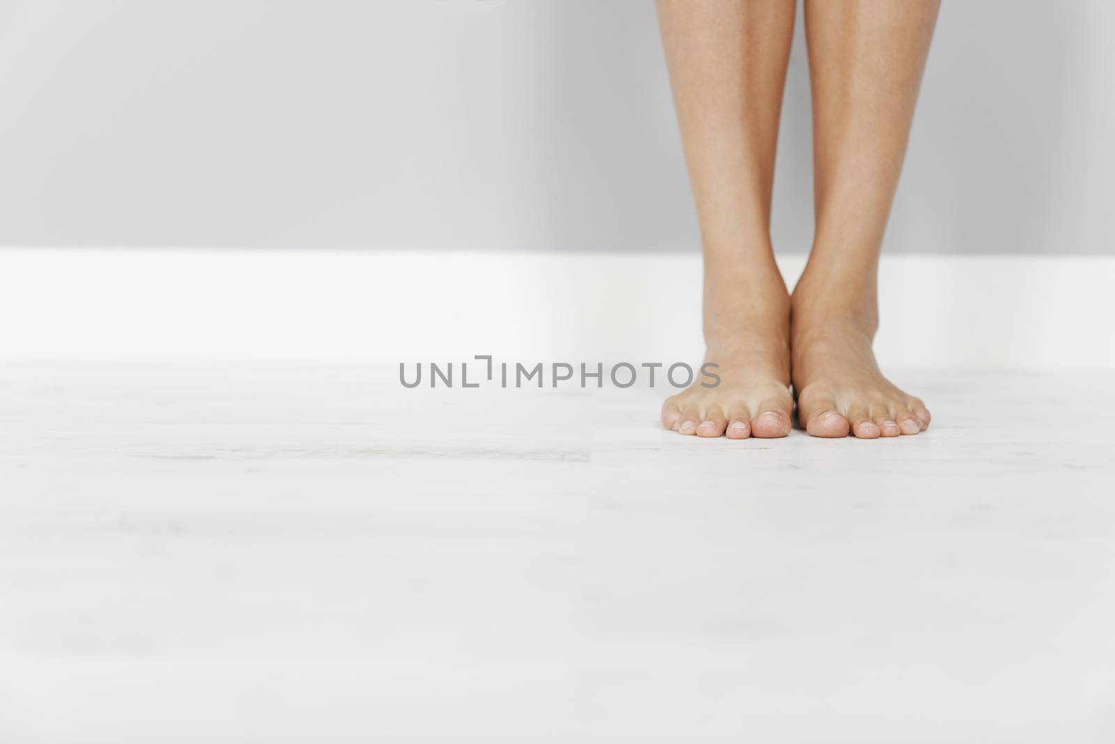 Young woman's legs on wooden floor.