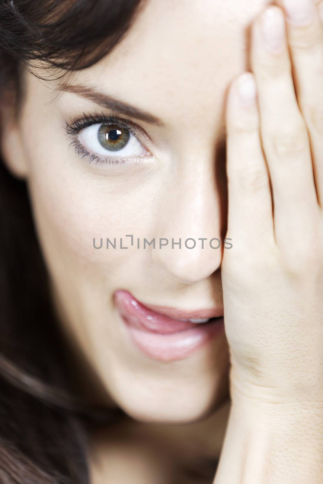 Young woman covering half her face with her hand.