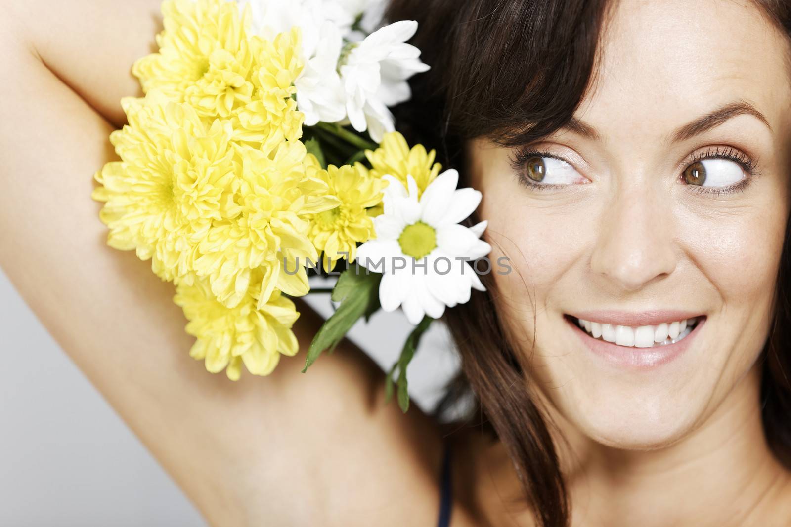 Woman holding flowers next to her head.