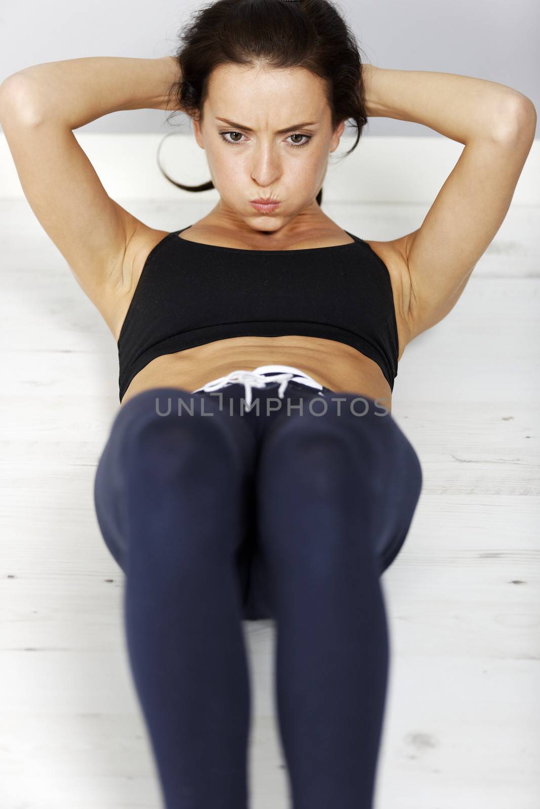 Young woman doing a sit-up on the floor.