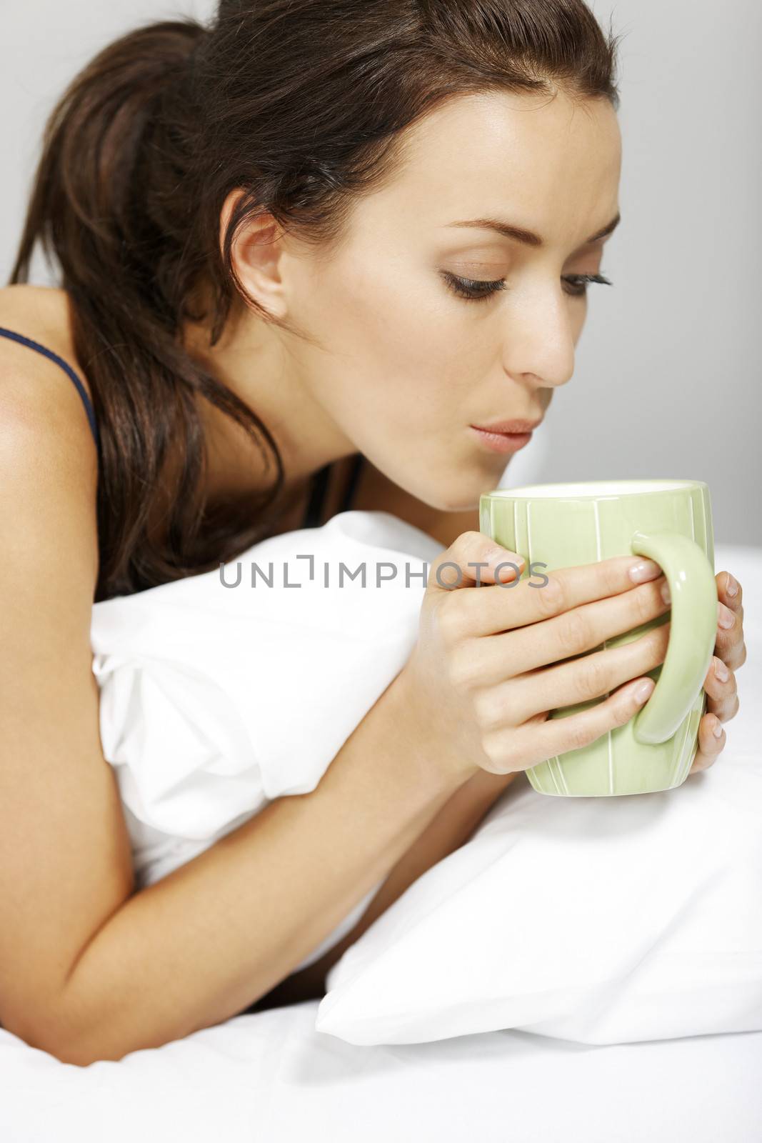 Woman drinking in bed by studiofi