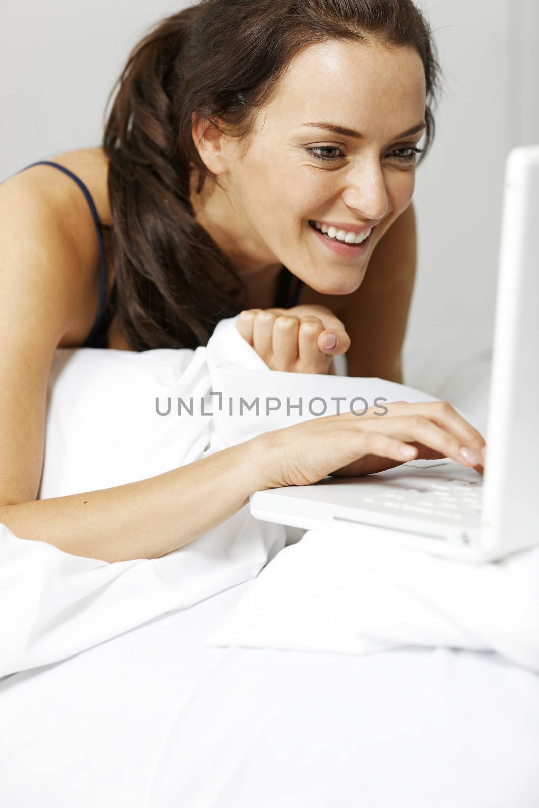 Young woman using her laptop in bed