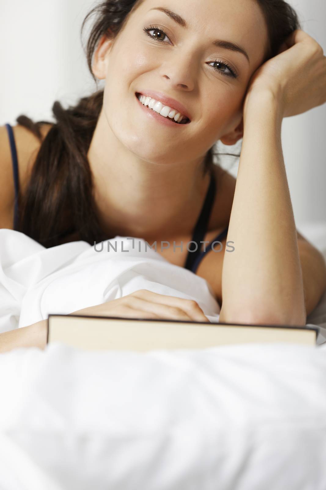 Young woman reading her book in bed