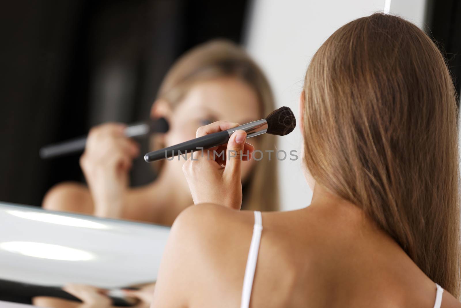 Attractive young woman in underwear applying make up in bathroom.