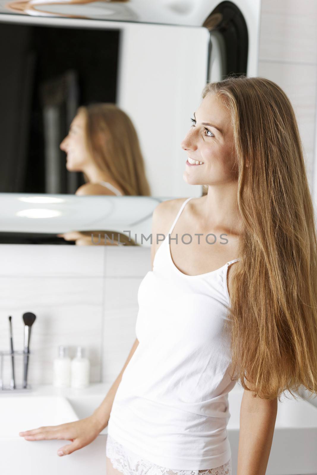 Beautiful young woman standing in her bathroom in underwear.