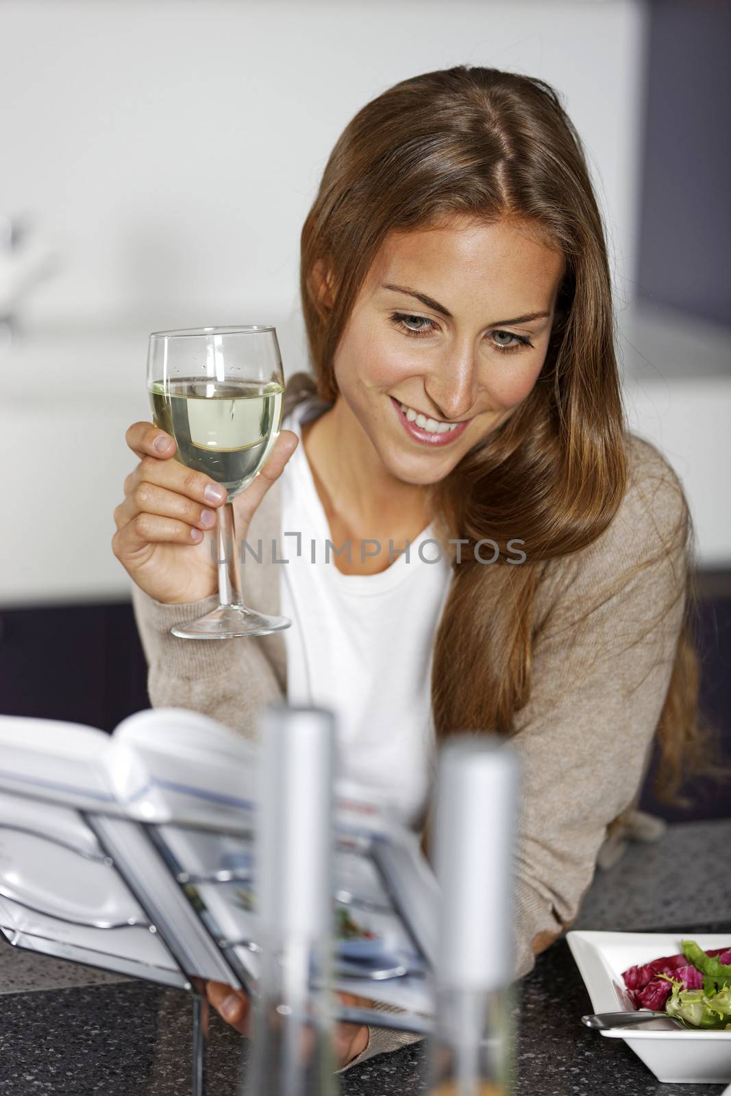 Woman preparing ingredients from a recipe book in her kitchen.