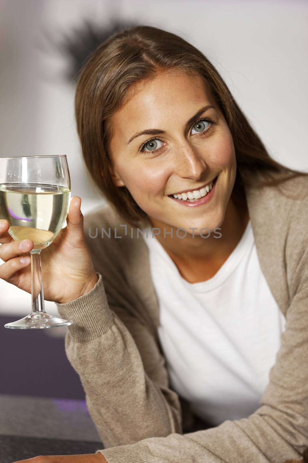 Attractive young woman enjoying a glass of wine in her kitchen.