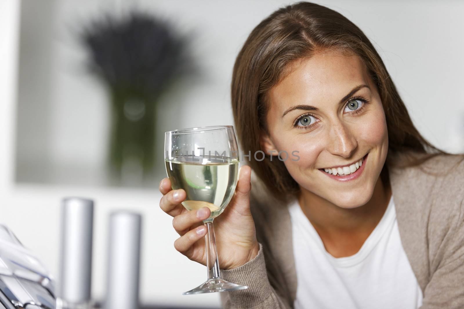 Attractive young woman enjoying a glass of wine in her kitchen.