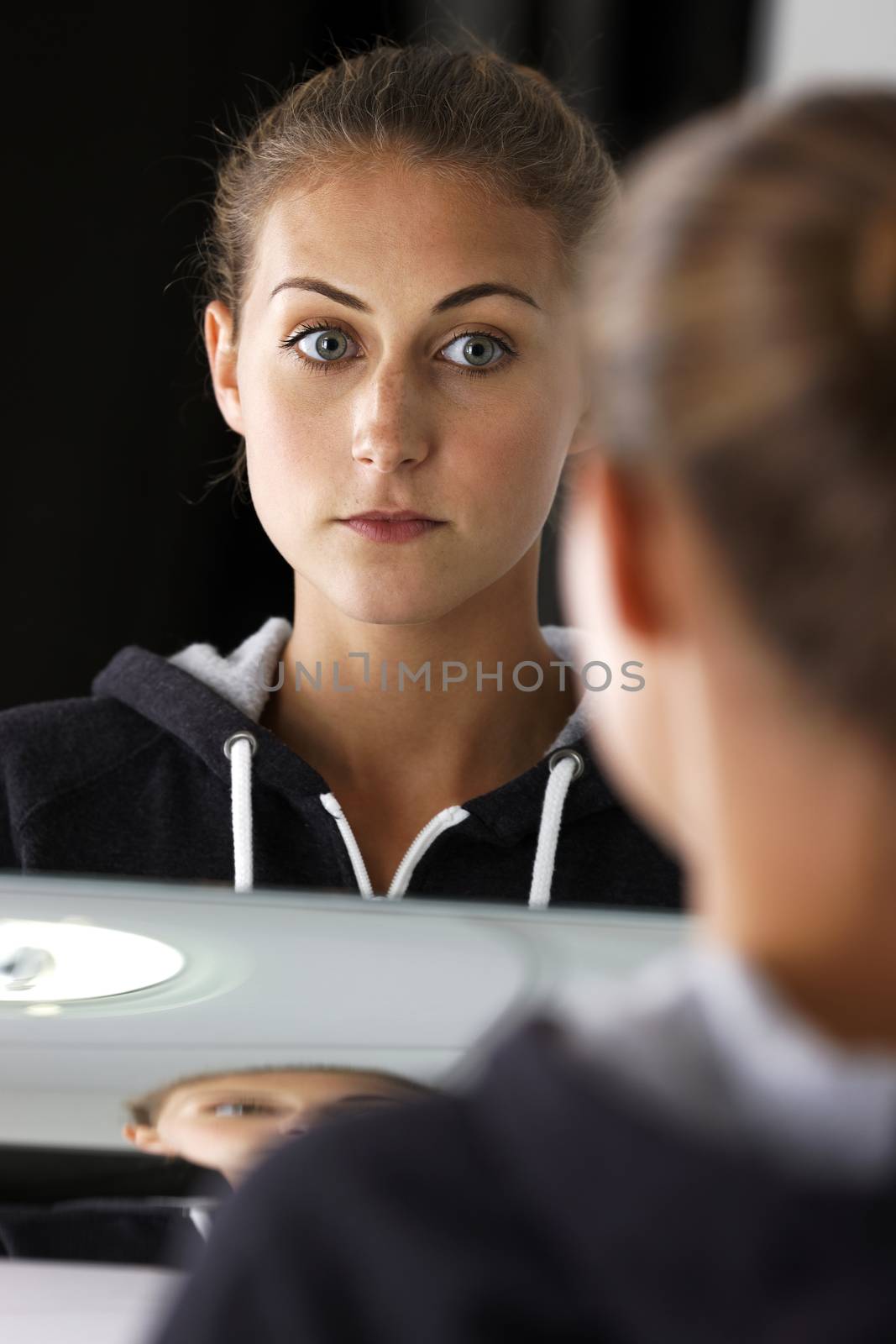 Young woman looking into a mirror in her bathroom
