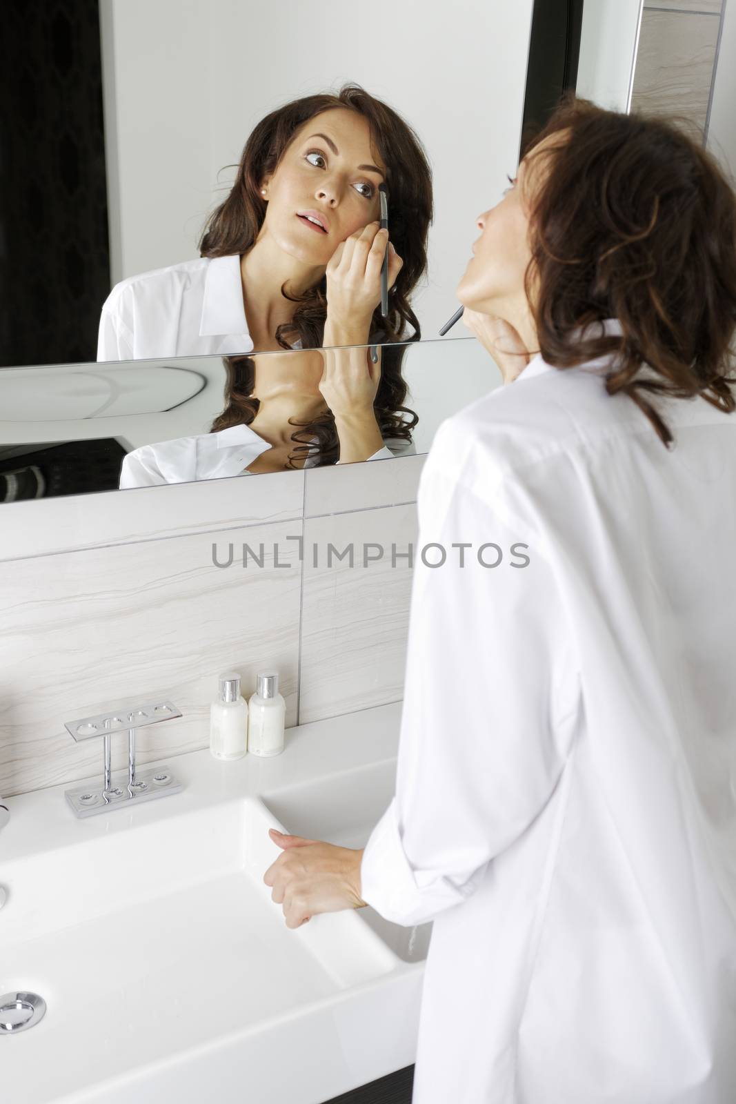 Woman doing her makeup by studiofi