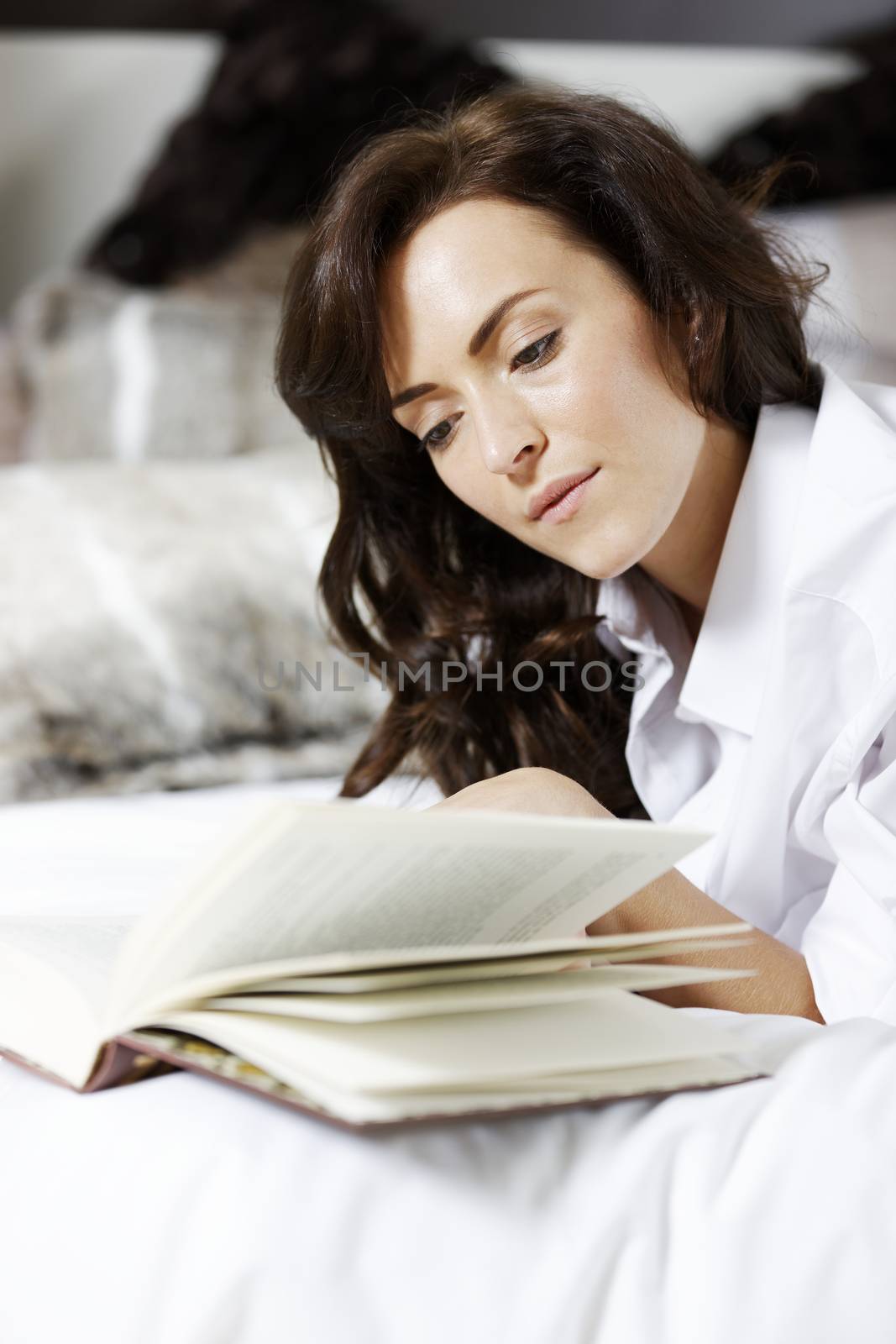 Woman reading book in bed by studiofi