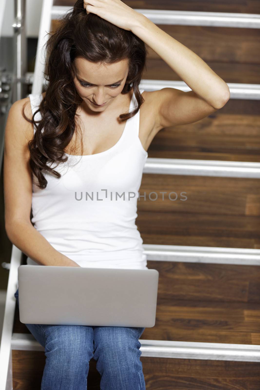 Woman using laptop while sitting on a staircase.
