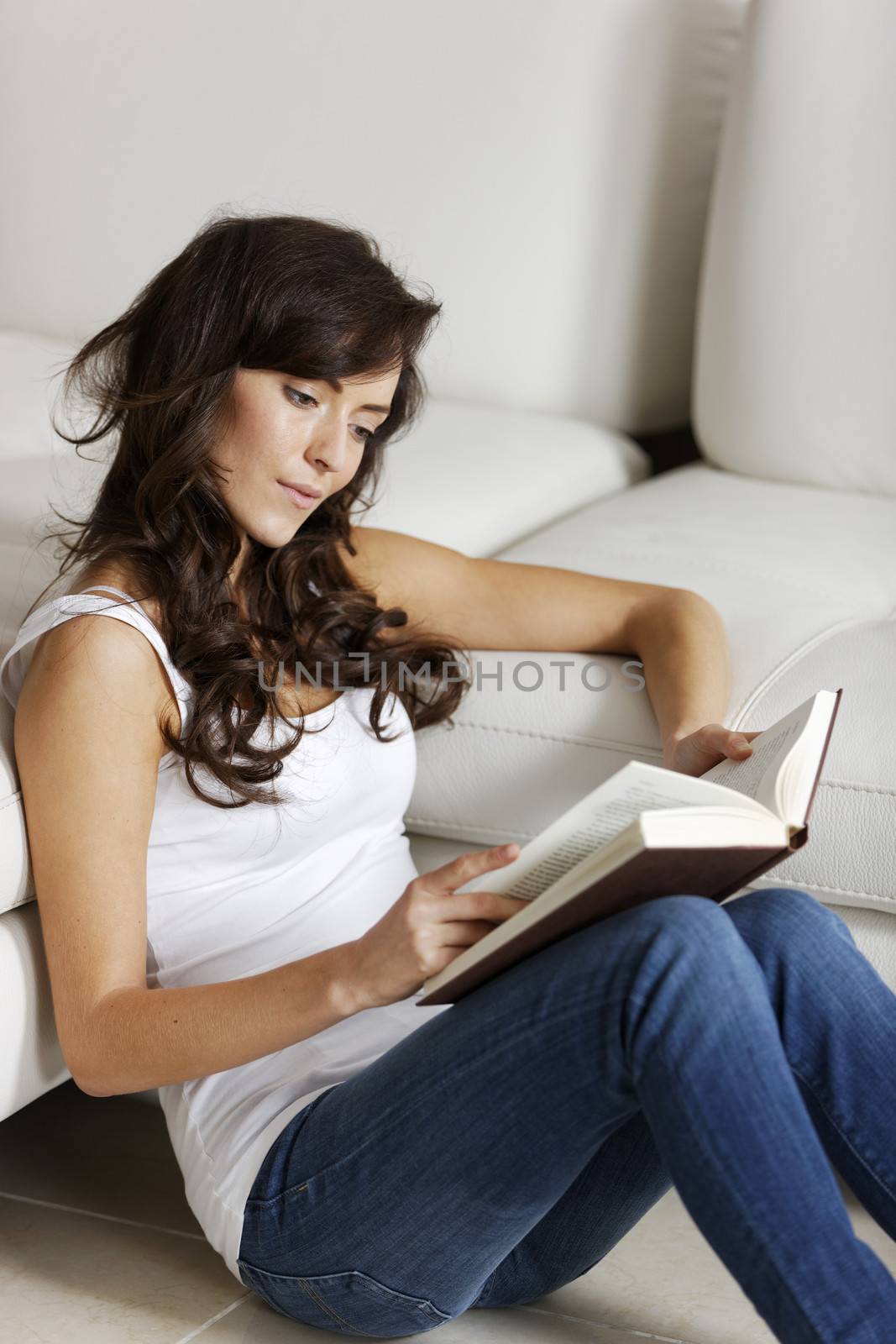 Young woman enjoying a good book in her living room.