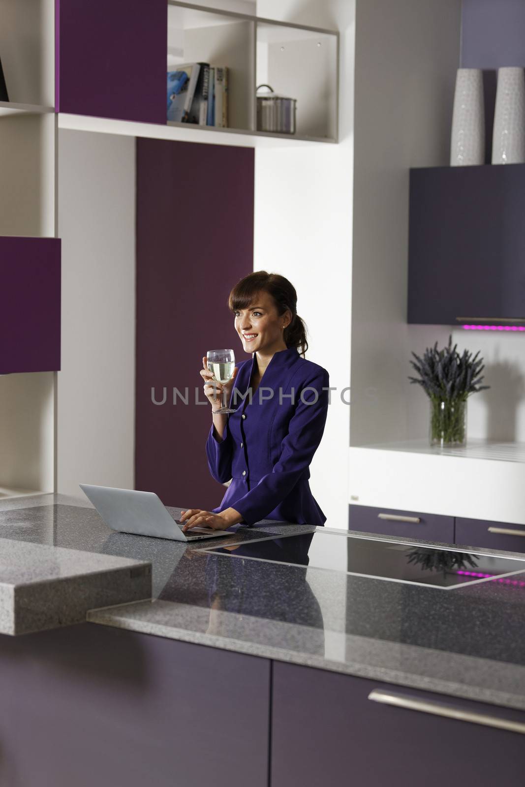 Smart business woman working on her laptop at home in kitchen.