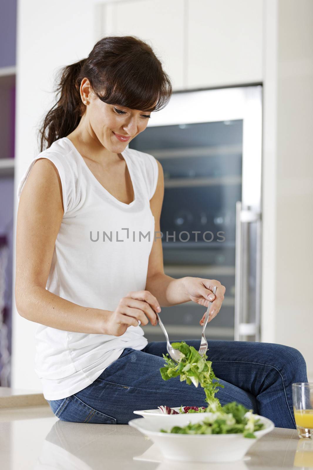 Woman eating salad at home by studiofi