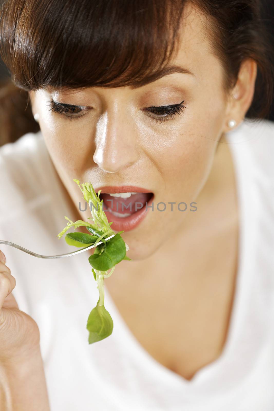 Woman eating salad at home by studiofi