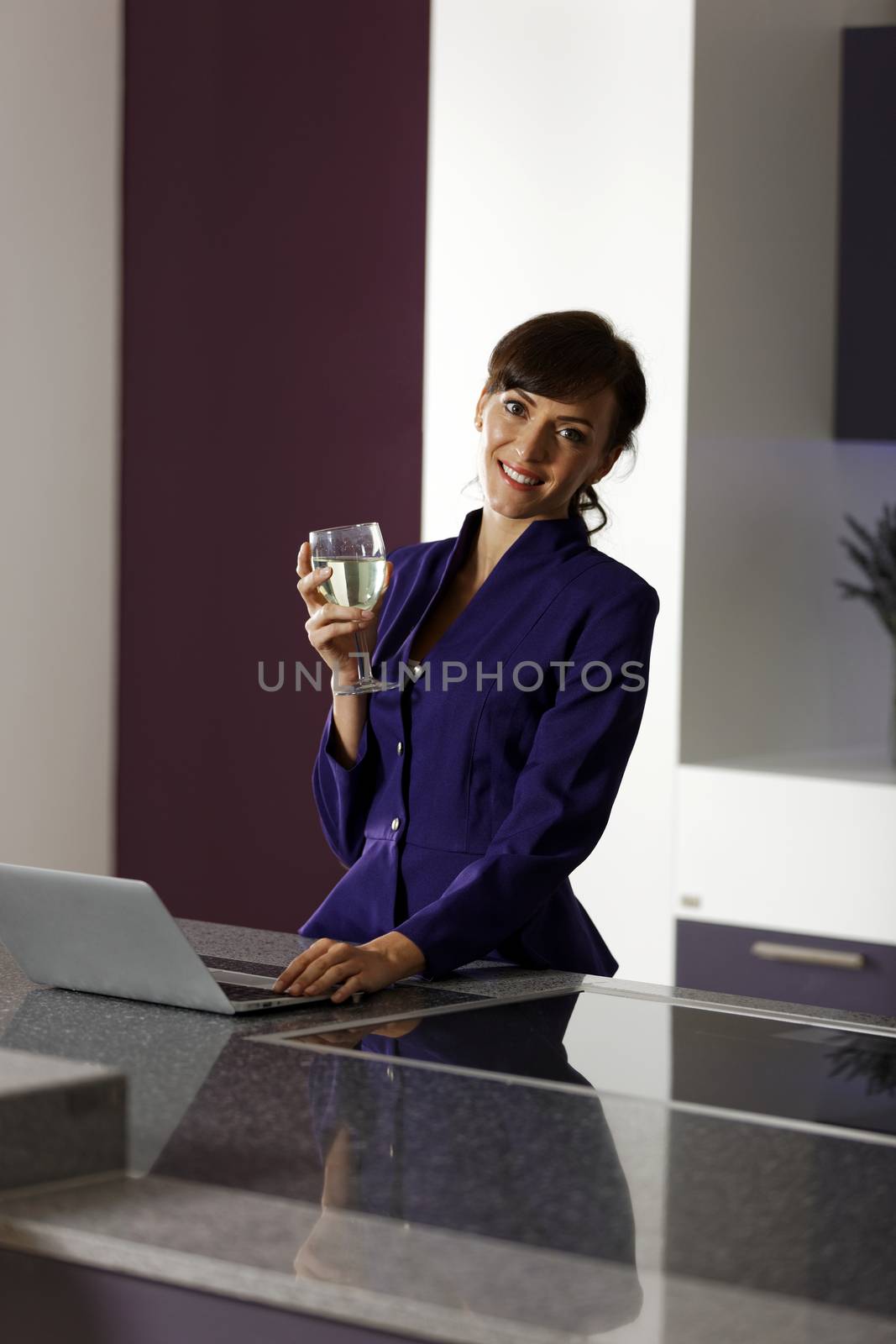 Smart business woman working on her laptop at home in kitchen.