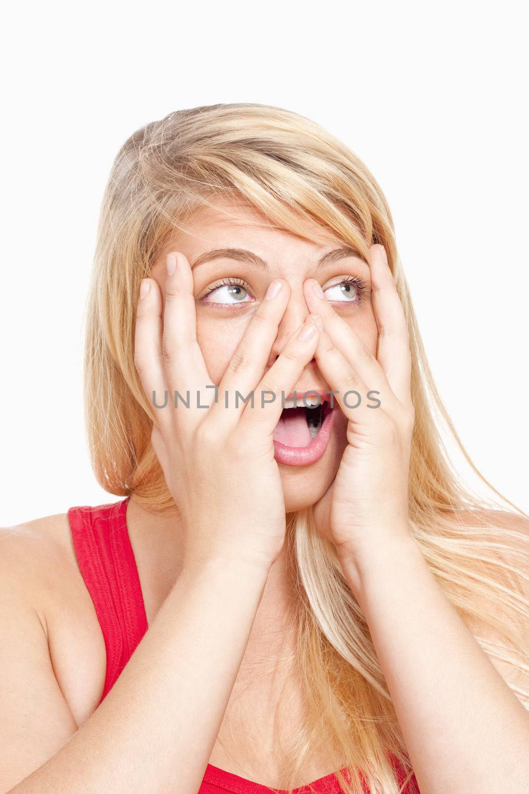 surprised young girl covering face with her hands peeking through fingers