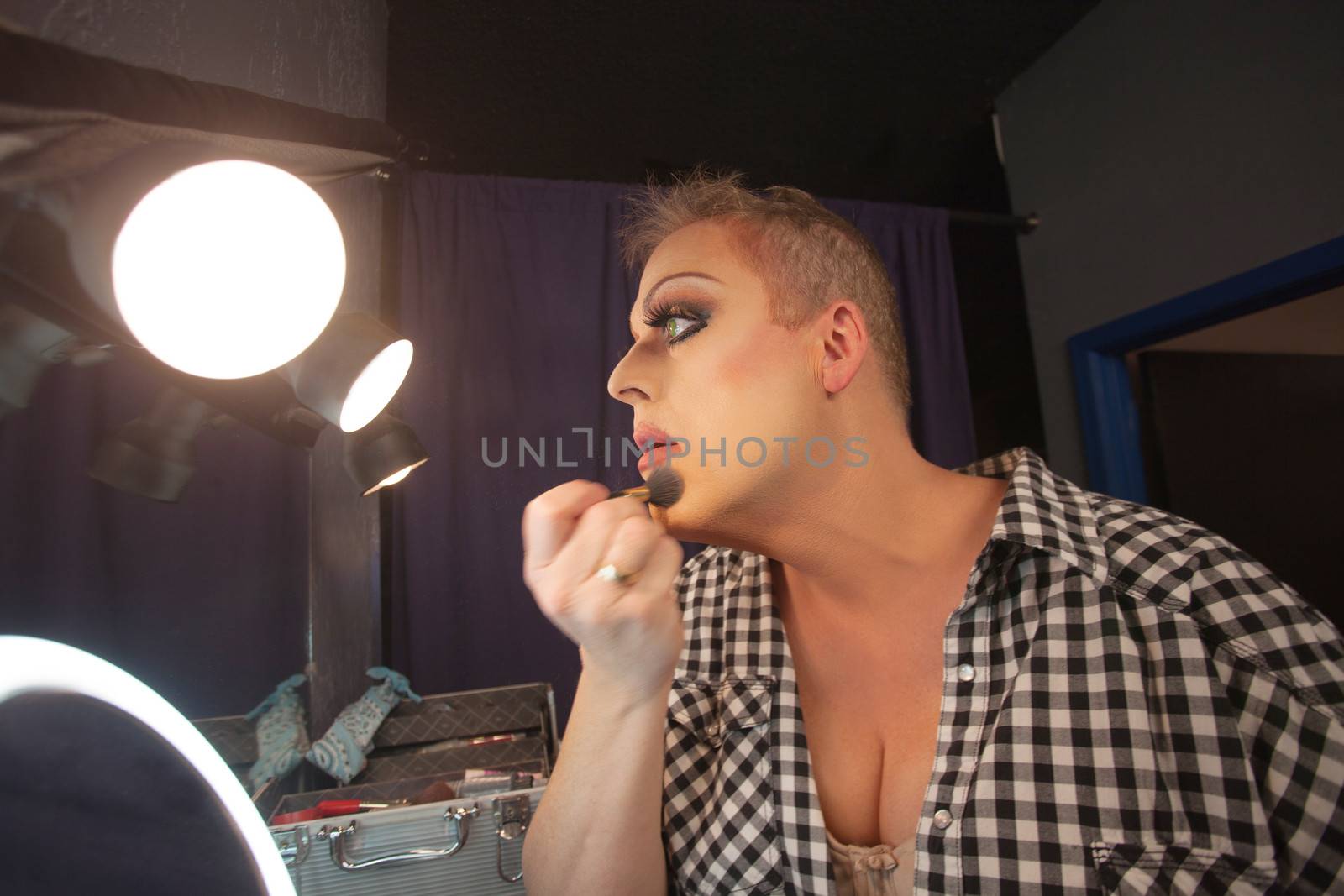 Man in dressing room preparing face for drag queen show