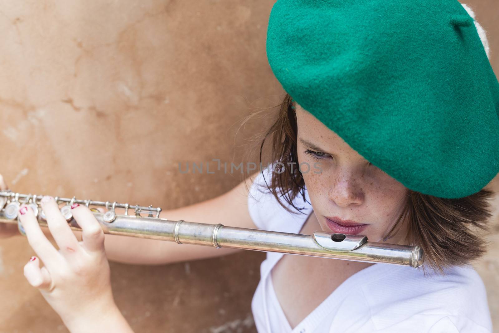 A young girl playing her instrument while wearing a fun hat.