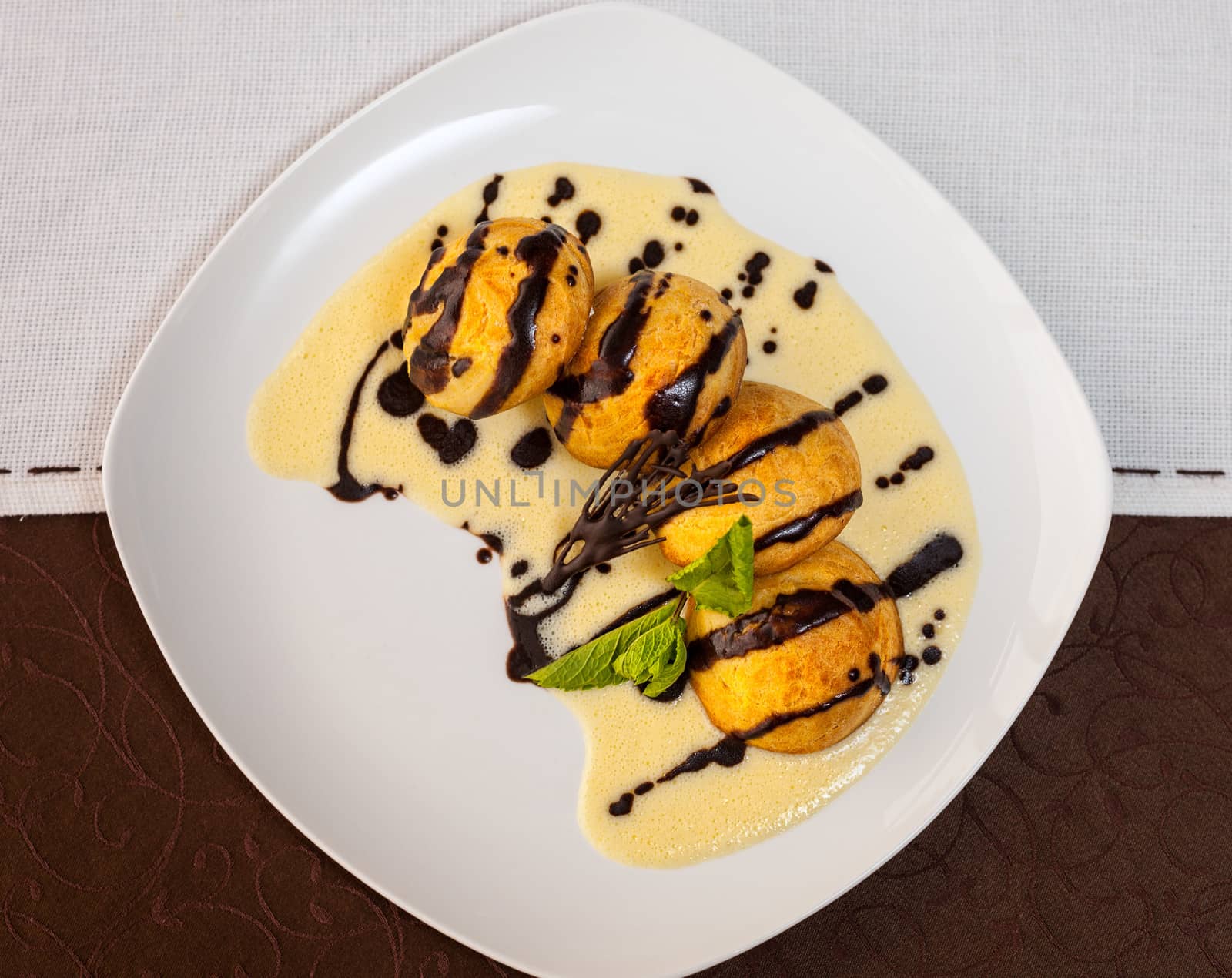 tasty dessert with chocolate, sweet sauce, cakes and mint on a white plate