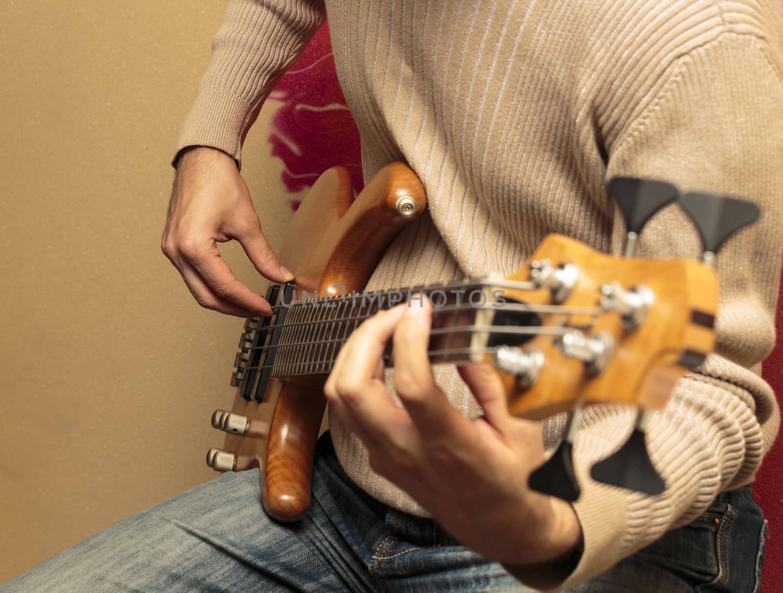 Guitarist sitting and playing a bass guitar by snowwhite