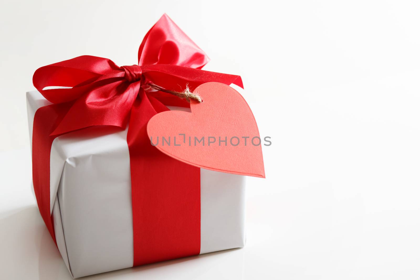 Gift box with red satin ribbon and heart tag