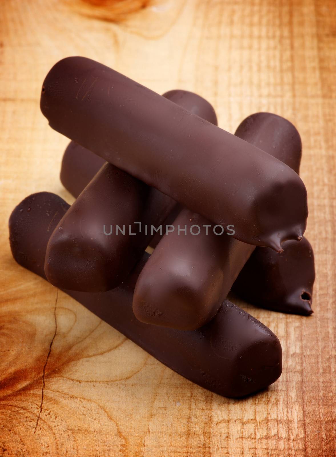 Stack of Ice Cream Sticks Glazed in Dark Chocolate closeup on Wooden background