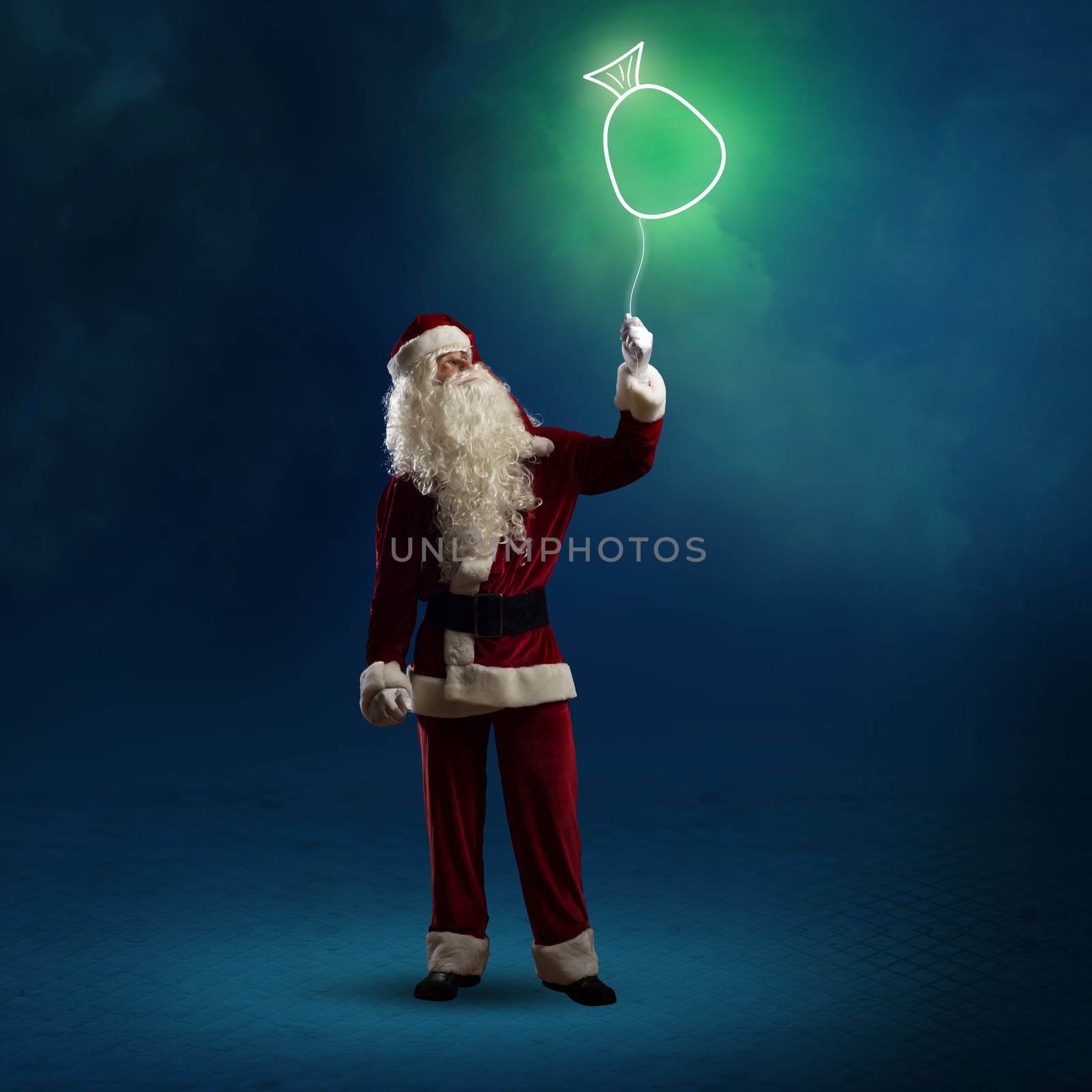 Santa Claus is holding a shining symbol of the bag with gifts on a string