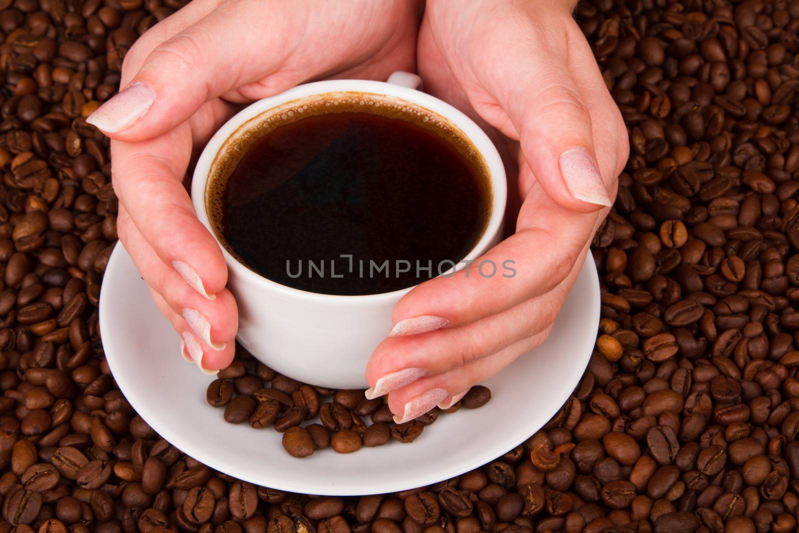 Woman holding hot cup of coffee, on coffee beans background
